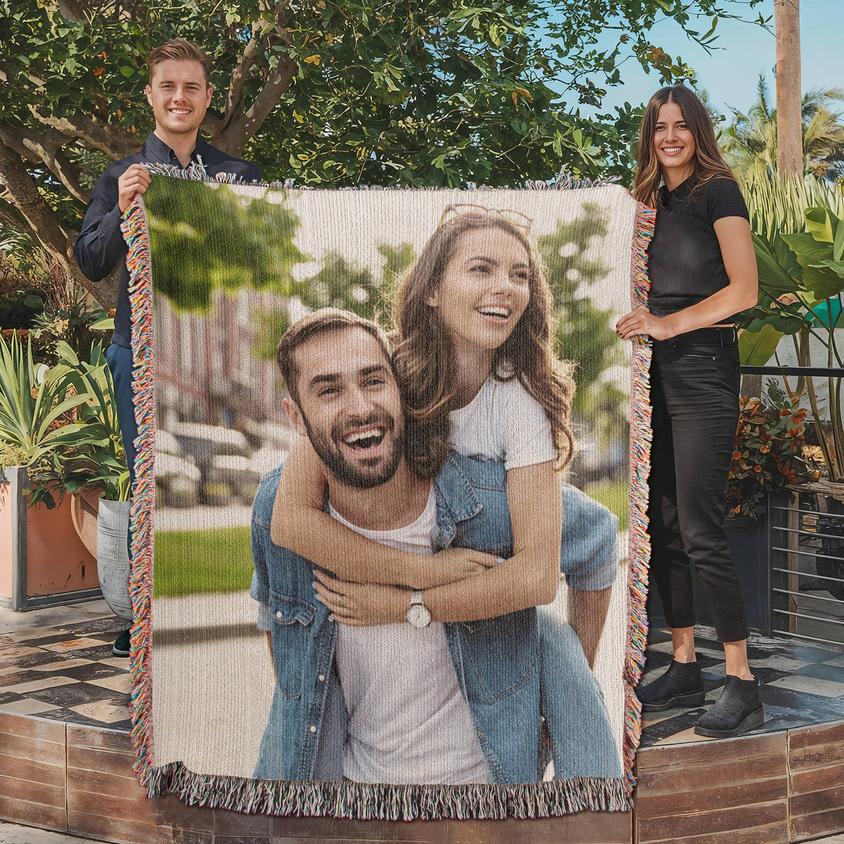 Two people holding the woven photo blanket in a garden
