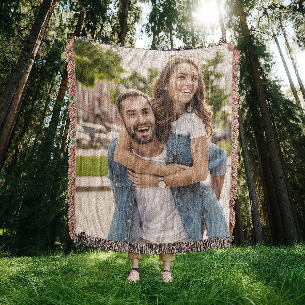 Custom woven photo blanket held up in a forest clearing